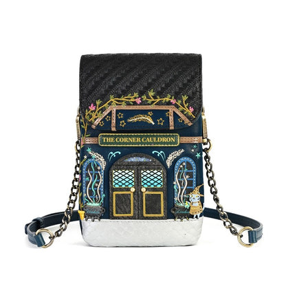 A small crossbody bag designed to look like the 'The Corner Cauldron' from Harry Potter, featuring a black carbon-fiber-textured top, a dark blue front with gold and teal window details, and a silver textured bottom, complete with a black leather strap and gold chain links.