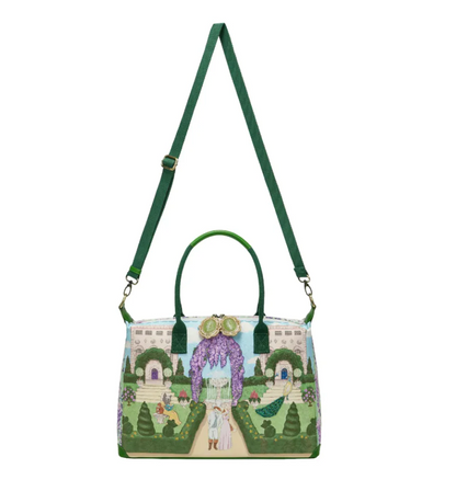 Woman holding a colorful handbag with a fairy tale design against a purple background with flowers.