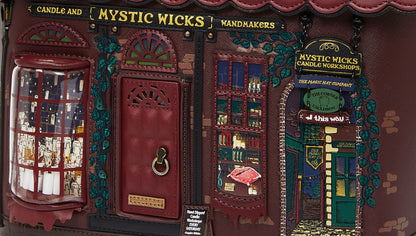 Decorative model of a candle shop named 'Mystic Wicks' with red door and window display.