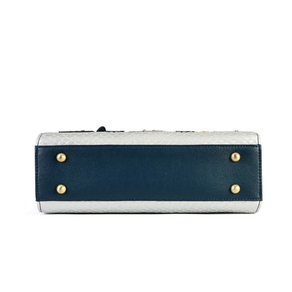 The bottom view of a rectangular clutch bag featuring a navy blue leather front panel with gold-tone metal studs, a textured light gray top and base, and a dark strap at the top.
