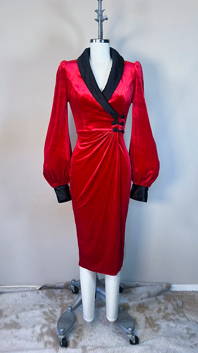 Red dress with black accents on a mannequin against a plain background