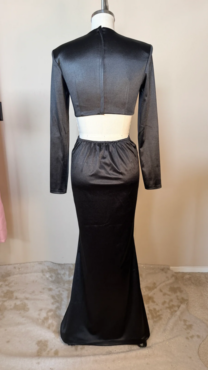 Black evening gown with sheer long sleeves on a mannequin against a neutral background
