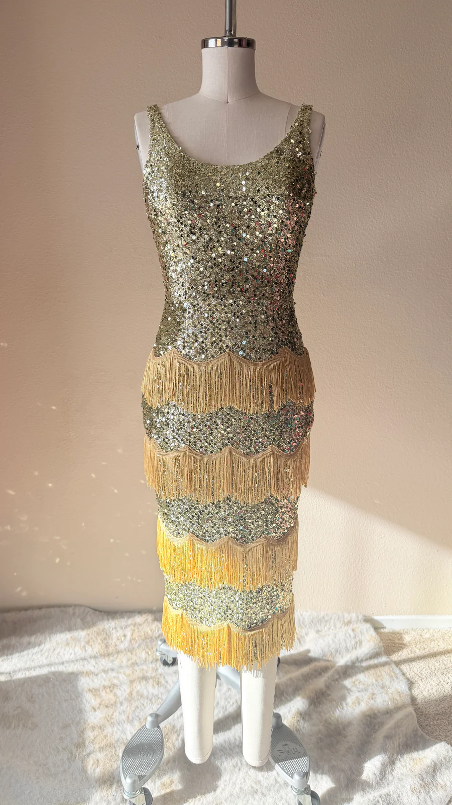 Gold sequin dress on a mannequin against a neutral background