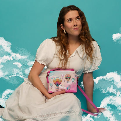 Woman holding a pink bag with hot air balloon design against a blue sky background