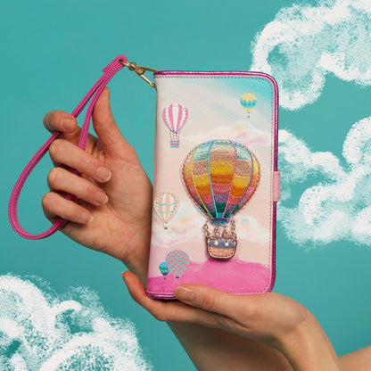 Hand holding a phone case with hot air balloon design against a teal background with cloud illustrations