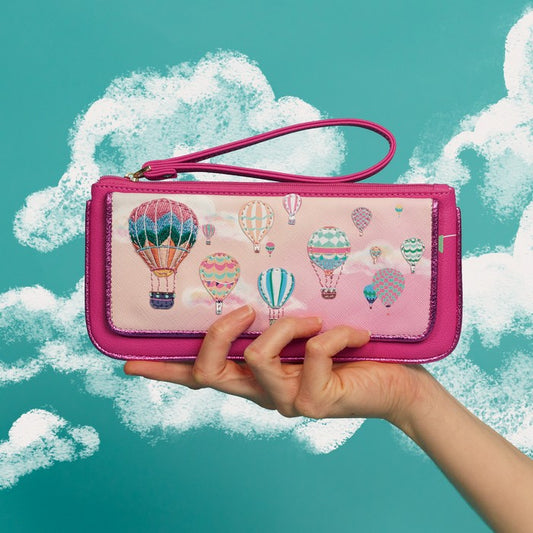 Pink wallet with hot air balloon design held by a hand against a teal background with clouds.