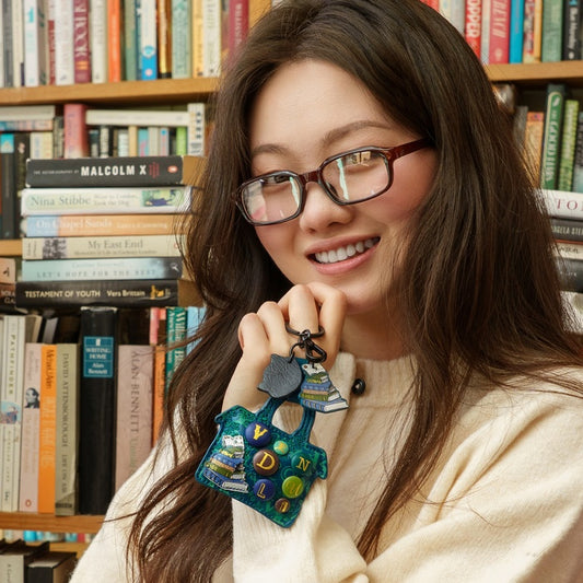 Woman holding a colorful keychain in front of a bookshelf