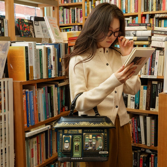 Woman reading a book in a library surrounded by bookshelves.