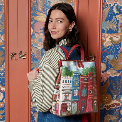 Woman holding a colorful bag with architectural designs against a decorative door.