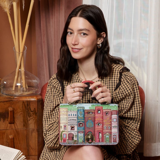 Woman holding a colorful box with architectural designs in a cozy indoor setting.