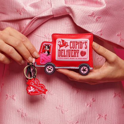 Red 'Cupid's Delivery' truck keychain held by hands on a pink textured background