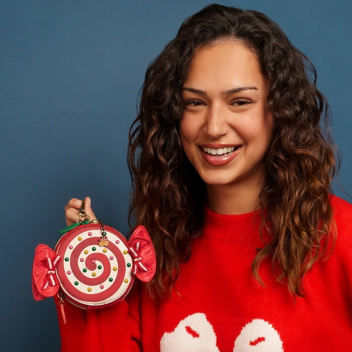 Woman wearing a red sweater with a candy-themed ornament against a blue background