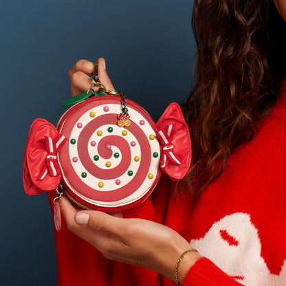 Person holding a red and white candy-themed handbag against a dark blue background