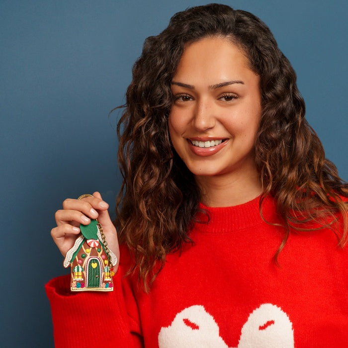 Woman in a red sweater holding a small decorative house against a blue background