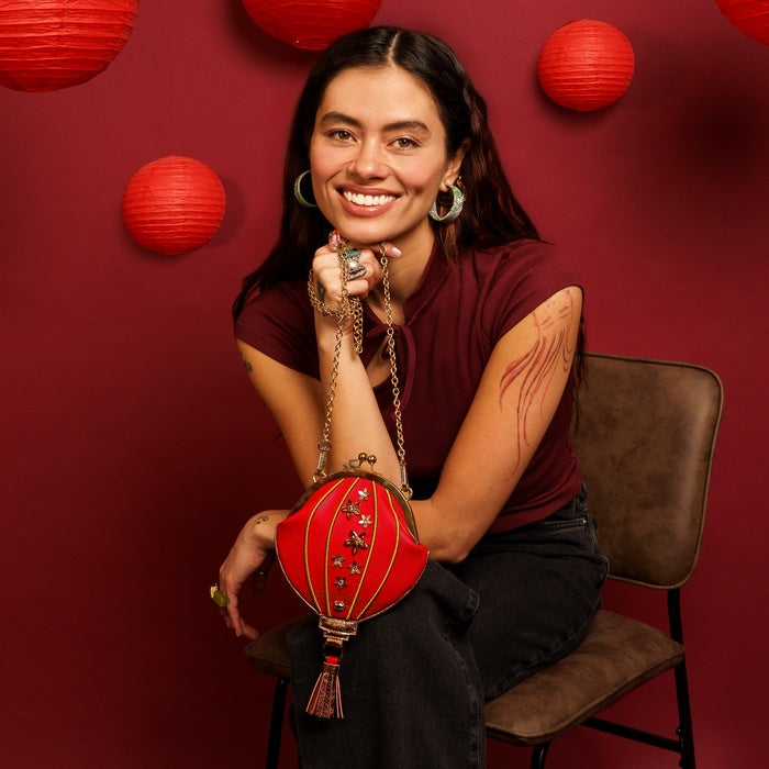 Woman holding a red lantern against a red background with additional lanterns.