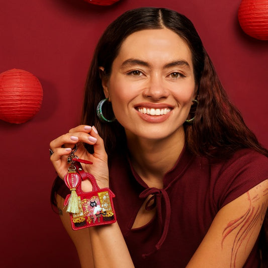 Woman holding a decorative keychain against a red background