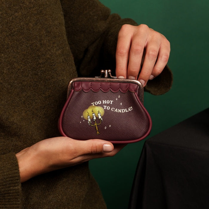 Person holding a purple purse with a humorous design against a green background