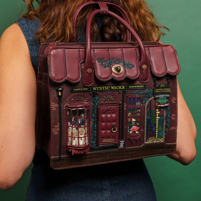 Person holding a detailed leather bag with decorative elements against a green background