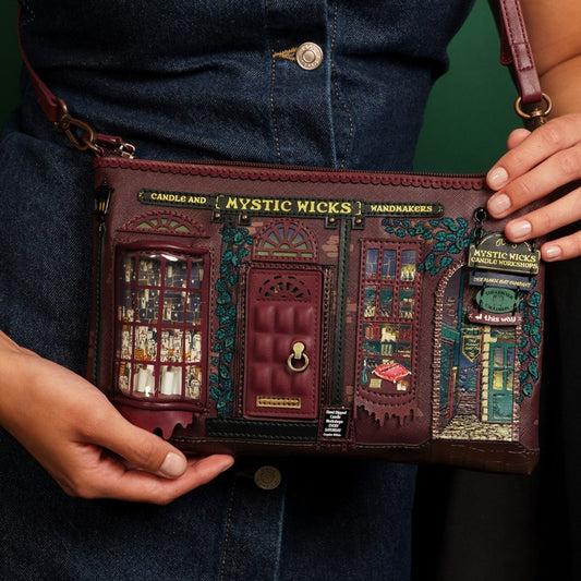 Handbag with detailed design held by a person wearing a denim jacket.