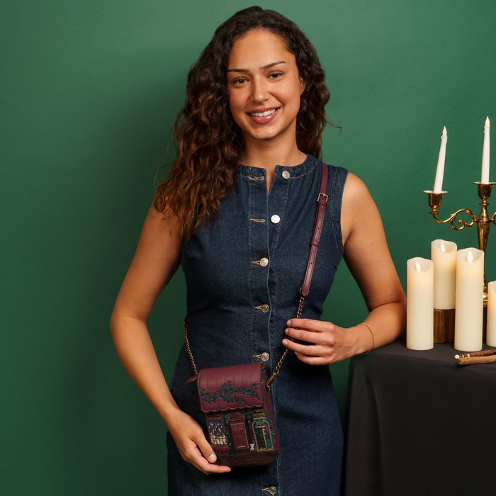 Woman holding a brown leather bag with candles on a table in the background