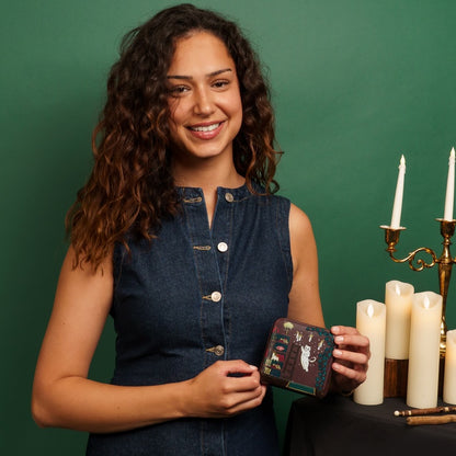 Woman holding a small wallet with candles and a candelabrum in the background