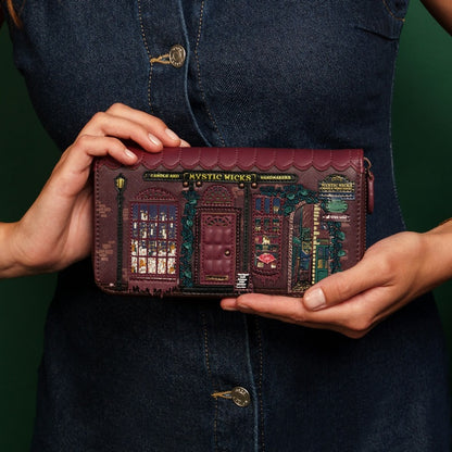 Person holding a decorative wallet with intricate designs against a dark background