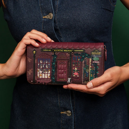 Person holding a decorative wallet with intricate designs against a dark background