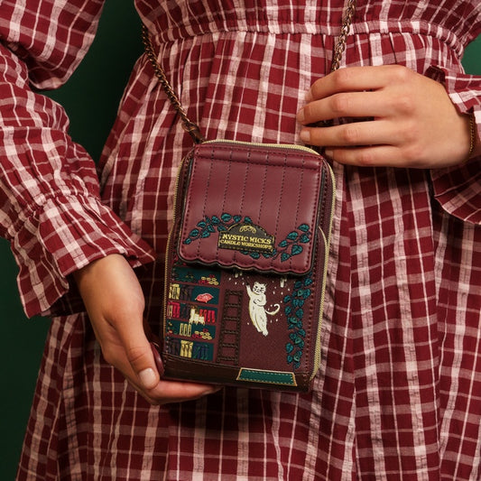 Person wearing a red and white checkered outfit holding a decorative brown bag with intricate designs.