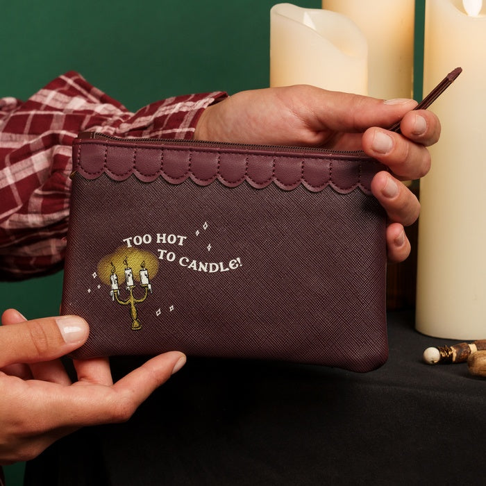 Person holding a brown pouch with 'Too Hot to Candle' text and graphic, against a dark background.