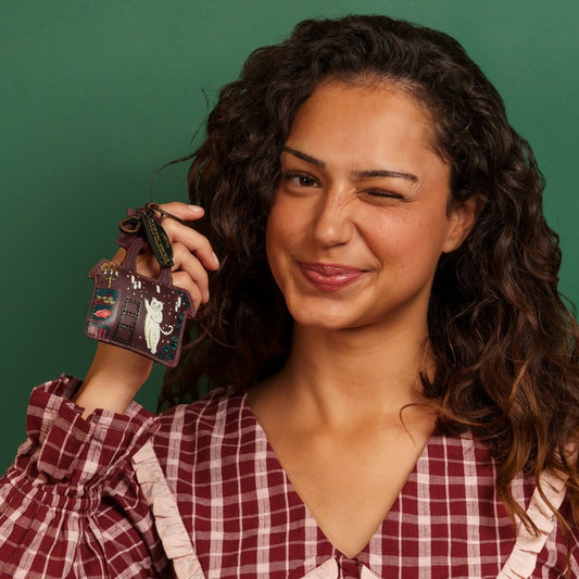 Woman holding a decorative keychain against a green background