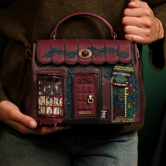 Handbag with decorative design held by a person against a dark background