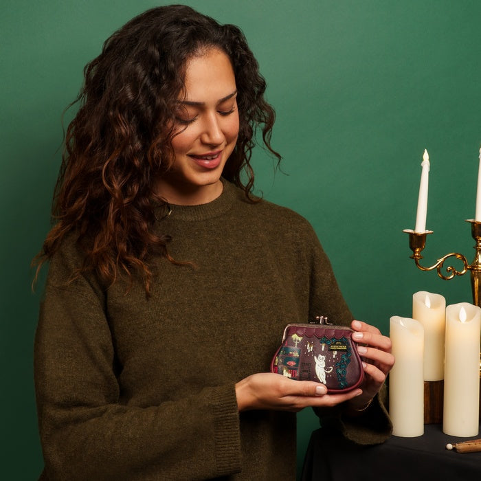 Woman holding a small pouch with candles and a candlestick in the background