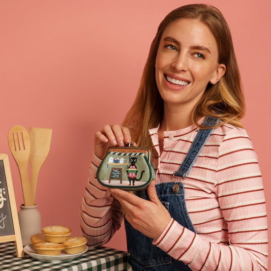 Woman holding a small bag with a cat design against a pink background