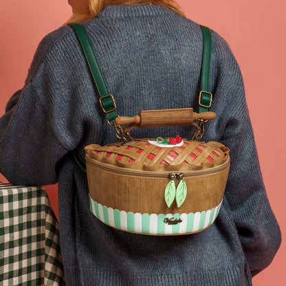 Person wearing a decorative woven bag with a rolling pin handle on a pink background