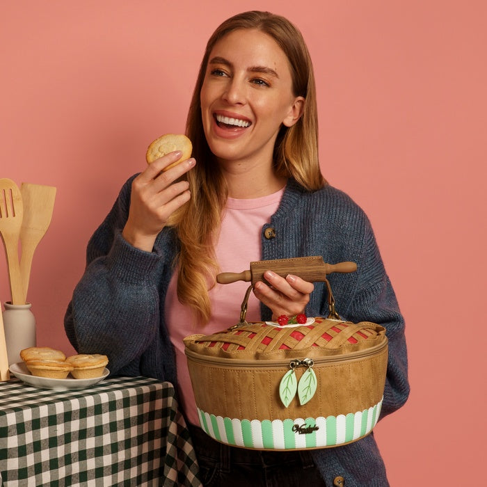 Woman holding a pie and a picnic basket against a pink background