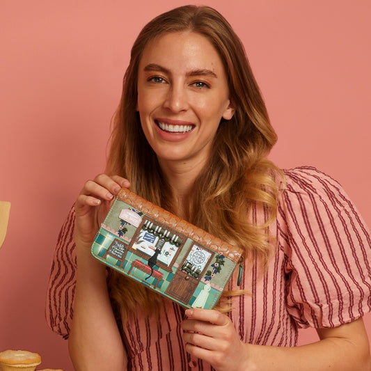 Woman holding a colorful wallet against a pink background