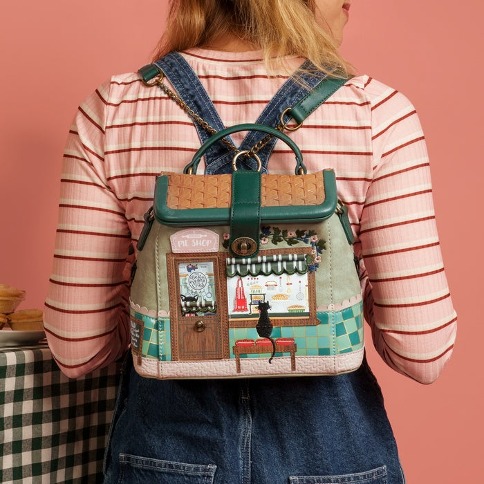Person wearing a backpack with a detailed design on a pink background