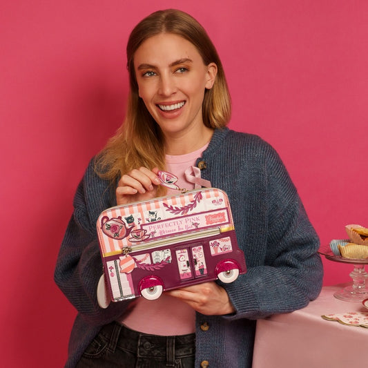 Woman holding a pink bus-shaped purse against a pink background