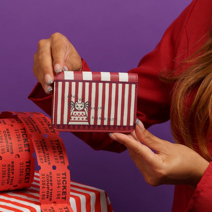 Person holding a red and white striped wallet with a purple background