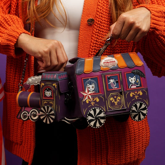 Person holding a colorful train-themed handbag with decorative elements.