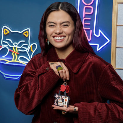 Woman holding a small bag with decorative elements in front of neon signs.