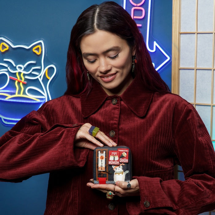 Woman holding a small model of a building with a cat on a blue background with neon signs.