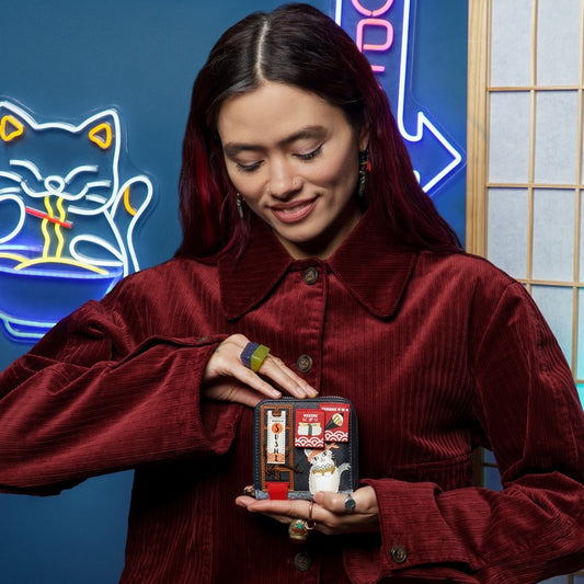 Woman holding a small model of a building with a cat on a blue background with neon signs.