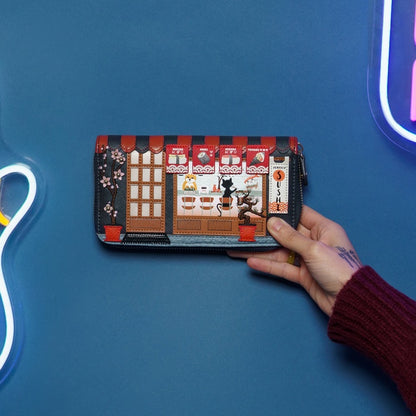 Hand holding a wallet with a detailed design against a blue background