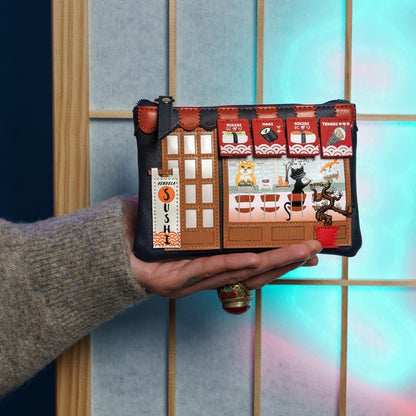 Hand holding a small pouch with sushi-themed design against a colorful background