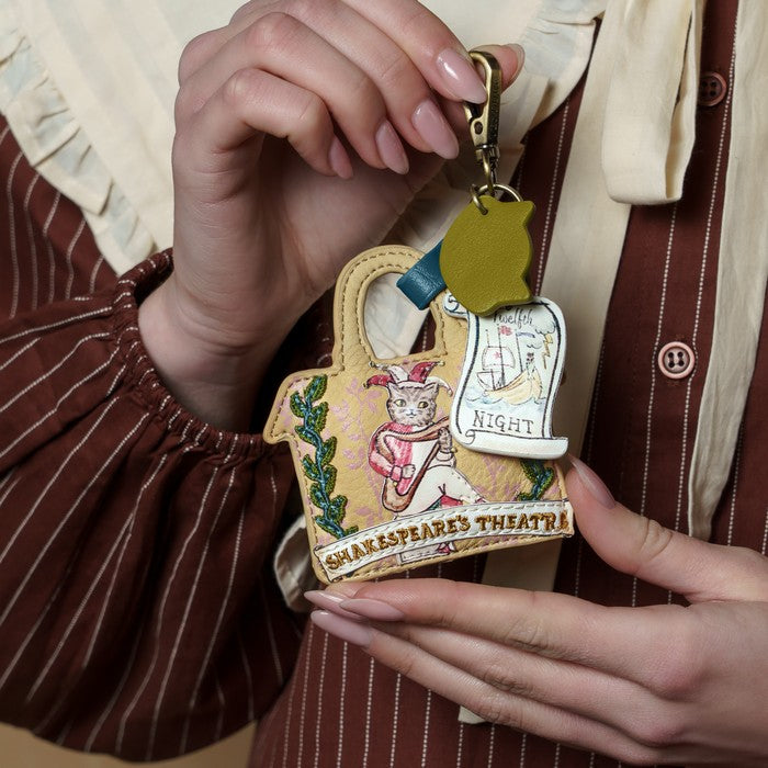 Person holding a keychain with a design of Shakespeare's Theatre and a cat in a hat.