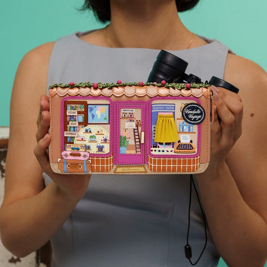 Person holding a colorful purse with a store design against a teal background