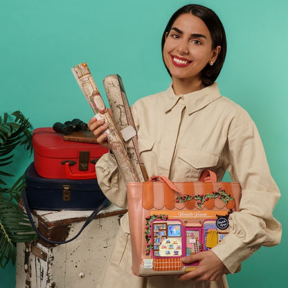 Woman holding a colorful bag with vintage suitcases and maps on a teal background
