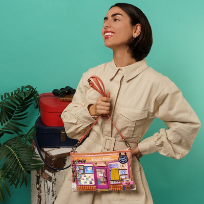 Woman holding a colorful handbag with a store design, standing against a teal background.