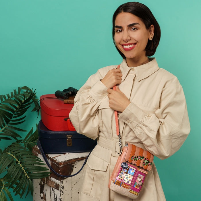 Woman holding a colorful handbag with vintage design against a teal background